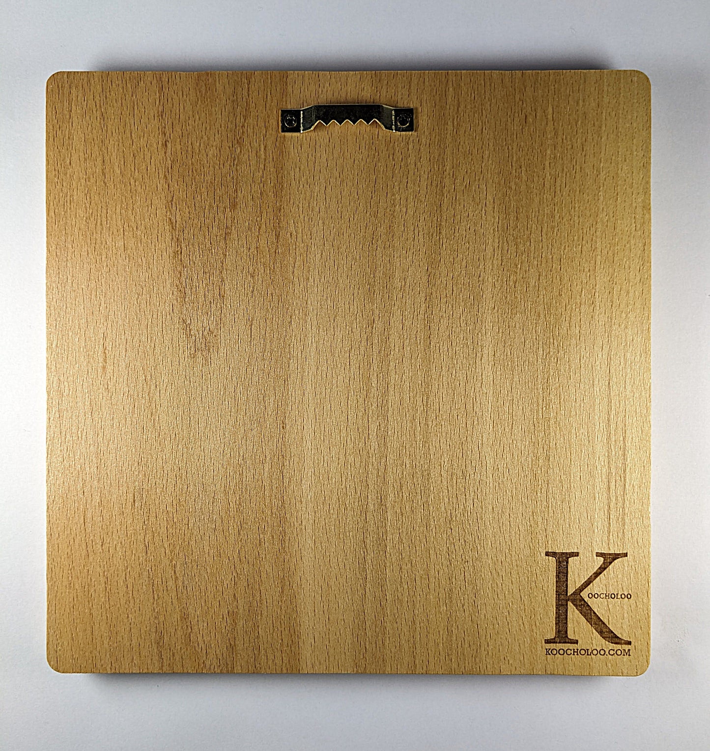 view of the back of wooden plaque with a piece of hardware to hang art on your wall and the logo of the business with a large letter K and the website koocholoo.com.