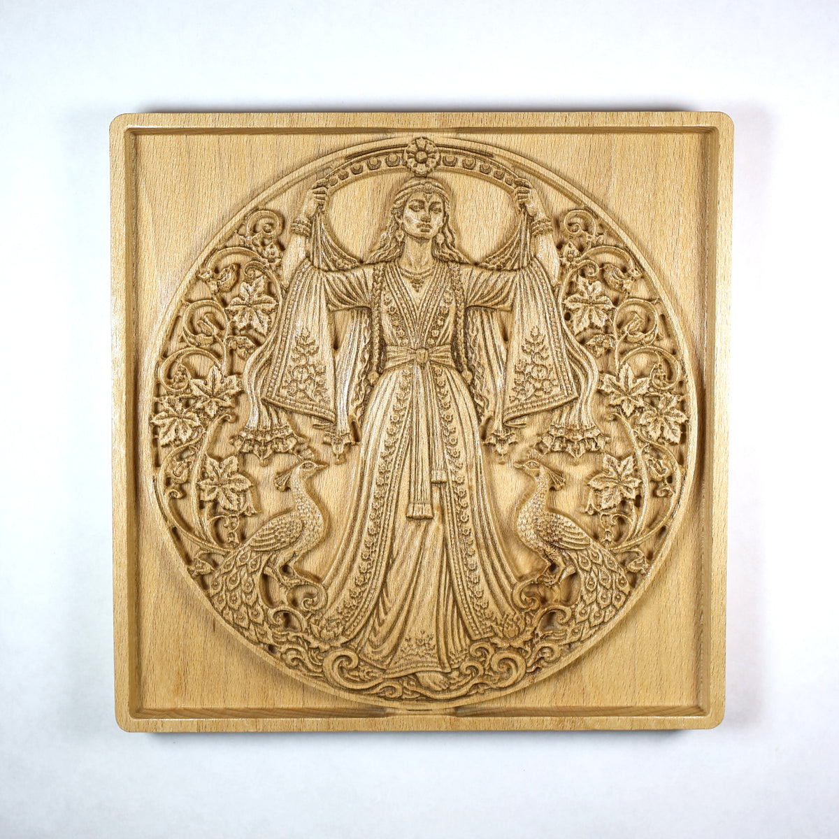 Front view of an Anahita wood relief showing the Persian goddess, floral vines, paired peacocks, round composition, and natural beech wood grain.