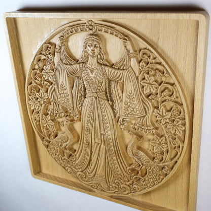 Angled view of the Anahita carving showing the goddess, ornate robe, peacocks, flowers, dimensional relief, and warm wood grain.