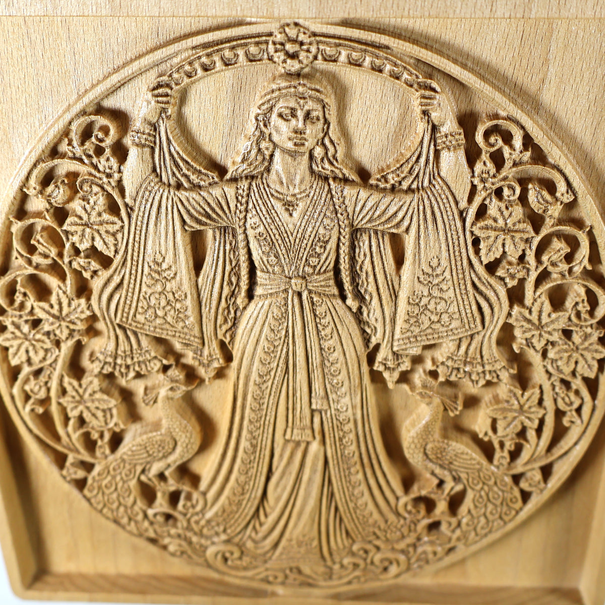 Close detail of the Anahita relief showing the goddess’s face, clothing, floral patterns, peacocks, and fine carved wood texture.