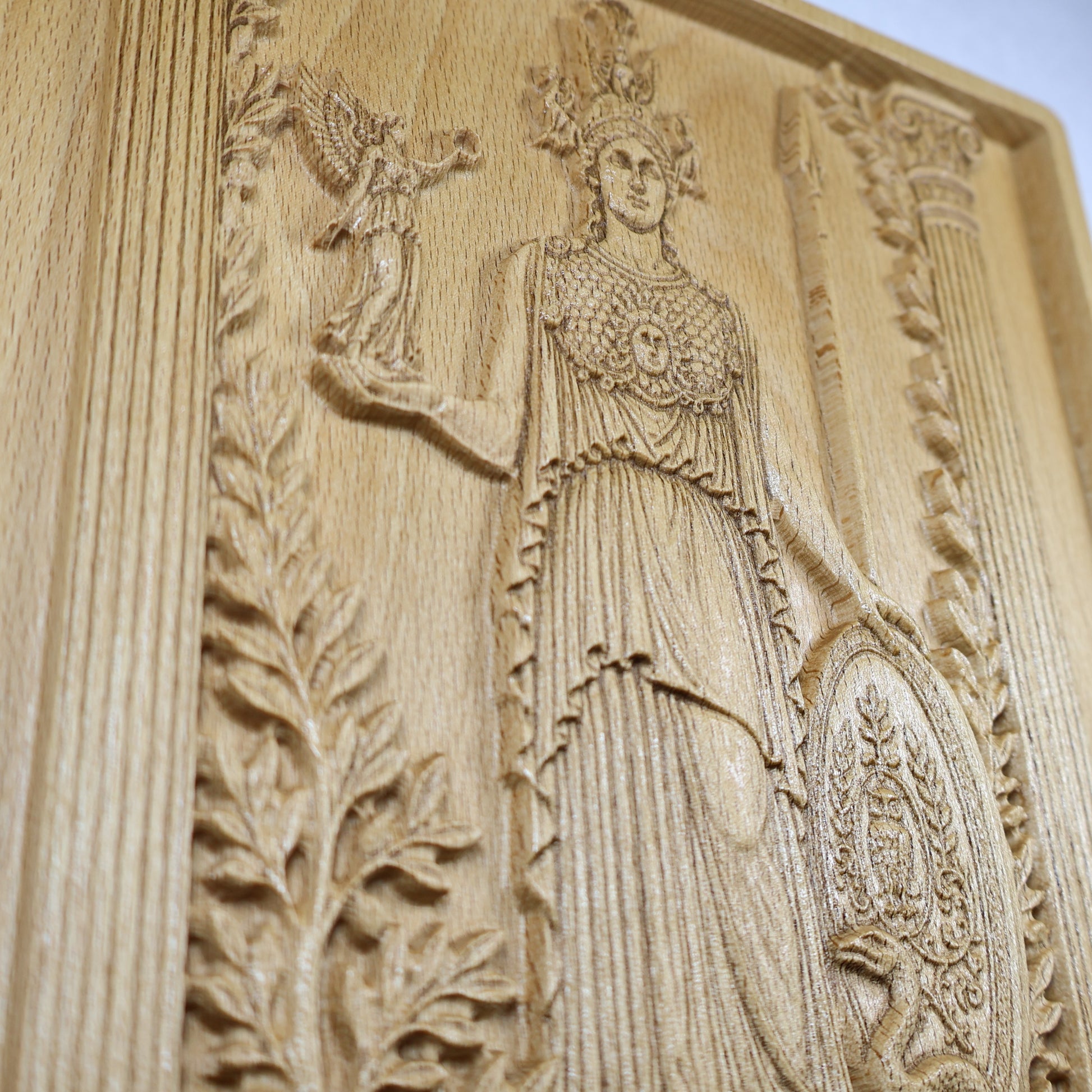 Close detail of the Athena wood relief showing her helmet, face, clothing, spear, shield, and fine carved texture.