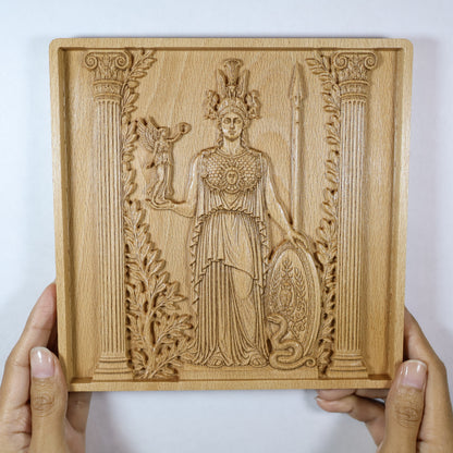 Athena wood relief held in hands for size reference, showing the framed Greek goddess carving and natural beech wood finish.