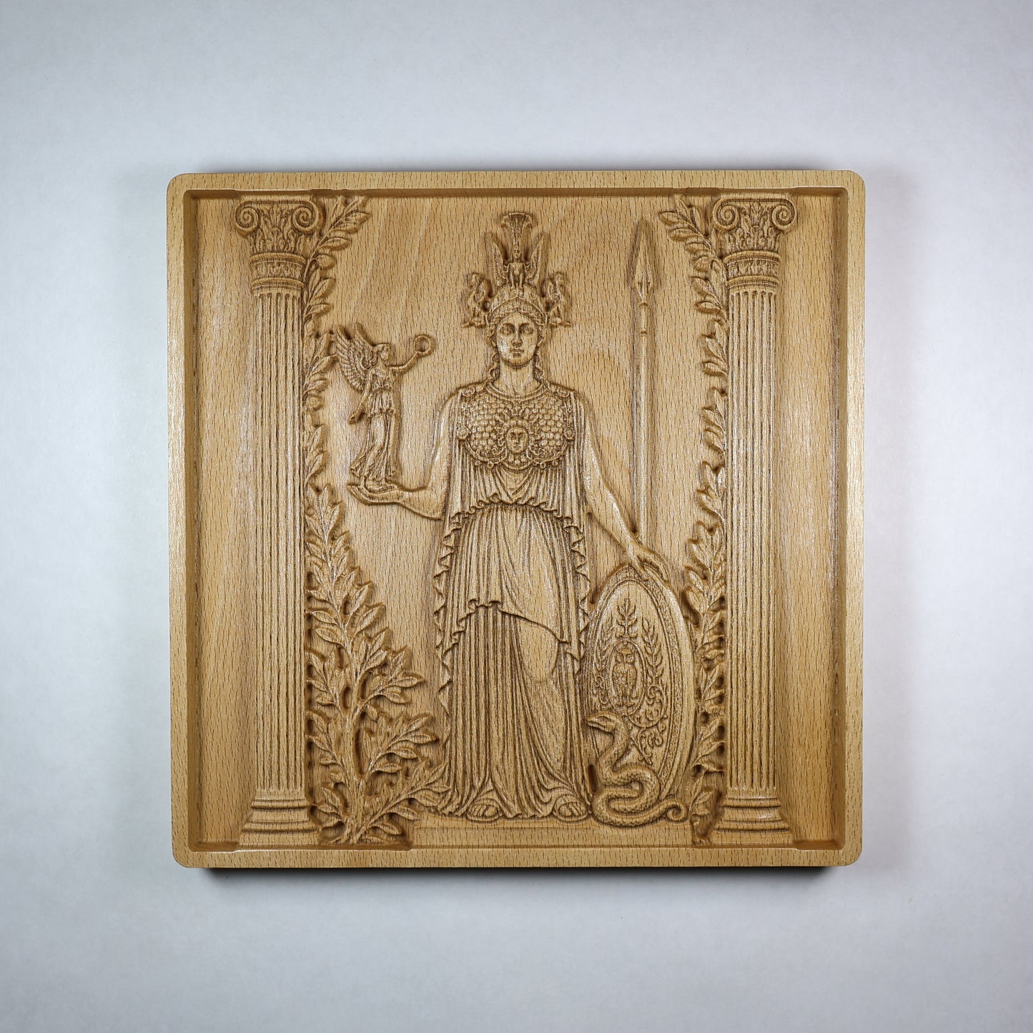 Front view of an Athena wood relief showing the Greek goddess with helmet, spear, shield, owl, olive branches, and classical carved details.