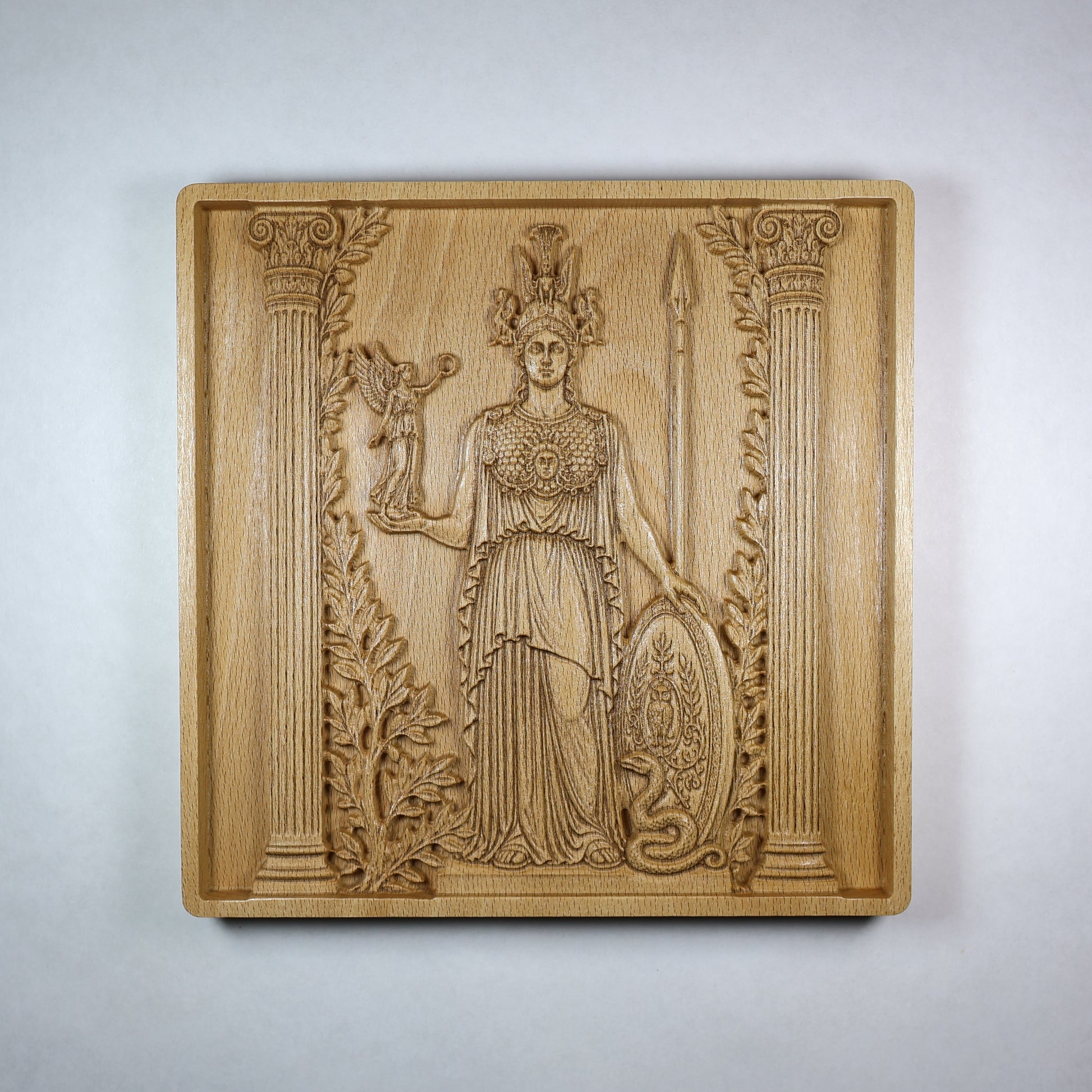 Front view of an Athena wood relief showing the Greek goddess with helmet, spear, shield, owl, olive branches, and classical carved details.