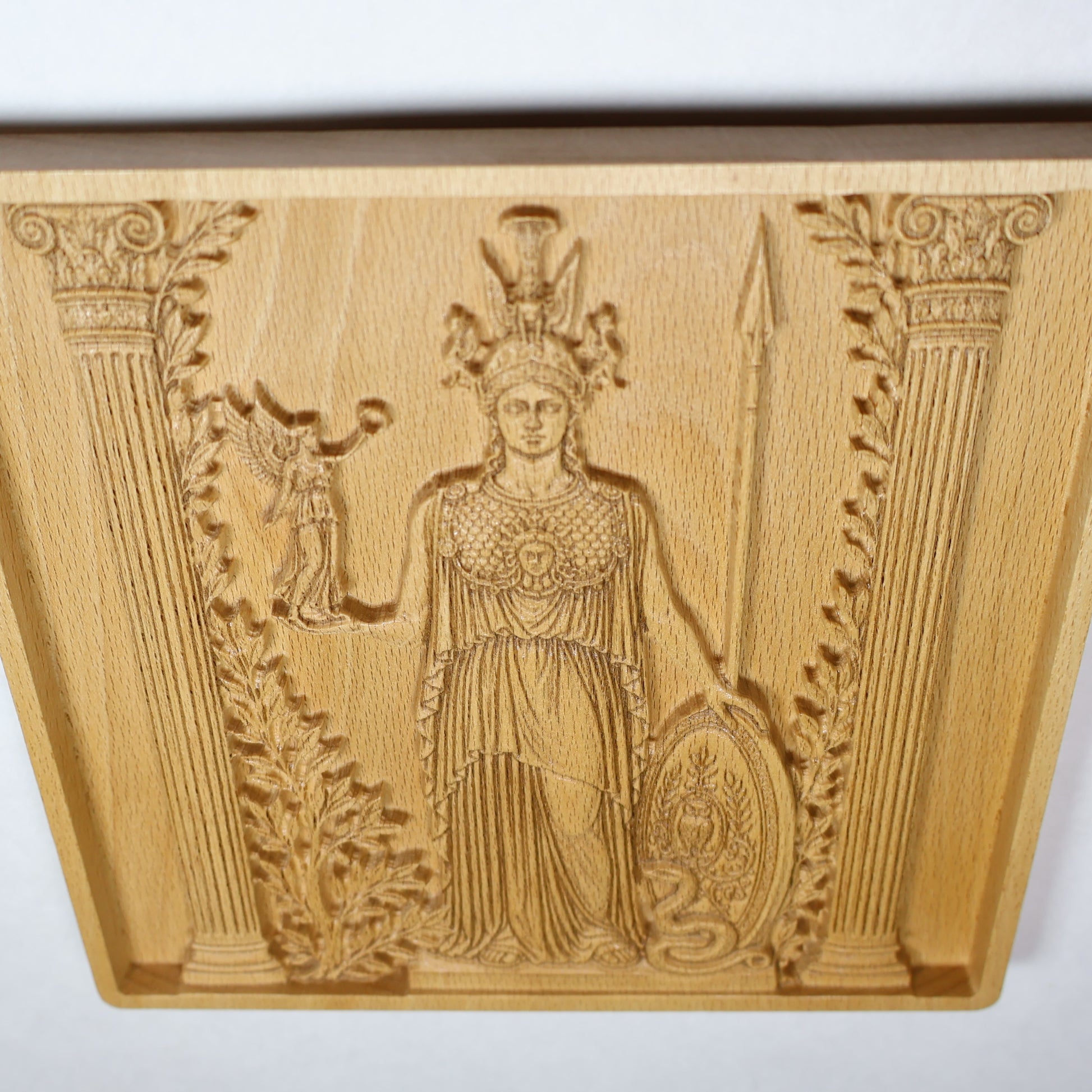 Detailed Athena wood carving showing the shield, helmet, spear, owl, olive details, Victory figure, and fine relief linework.