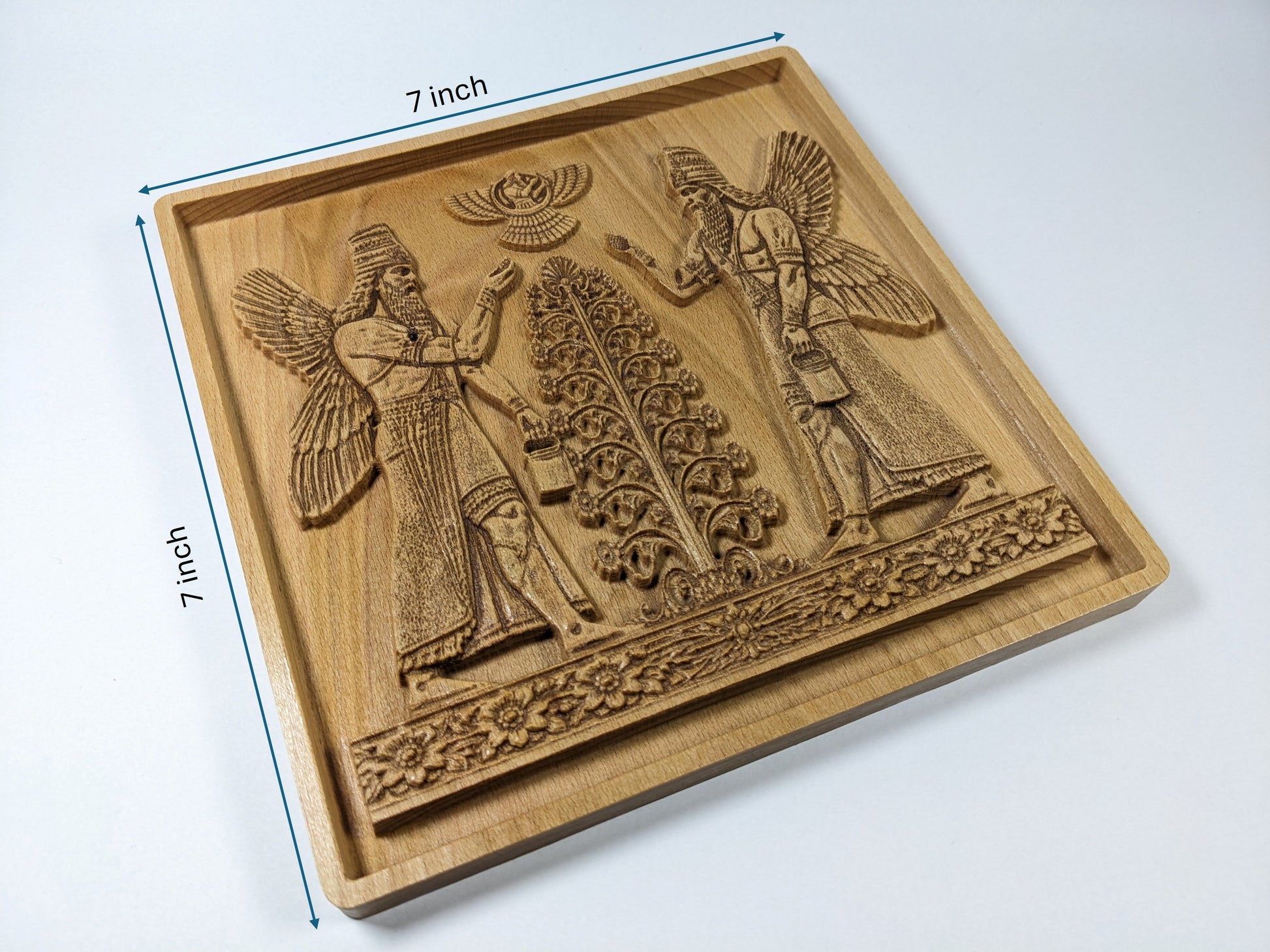 Size reference for Assyrian Sacred Tree beech wood wall art showing 7 inch by 7 inch square carved plaque with mirrored Apkallu guardian figures, central tree of life, Ashur winged disc, floral border frieze, recessed frame, and visible plaque thickness
