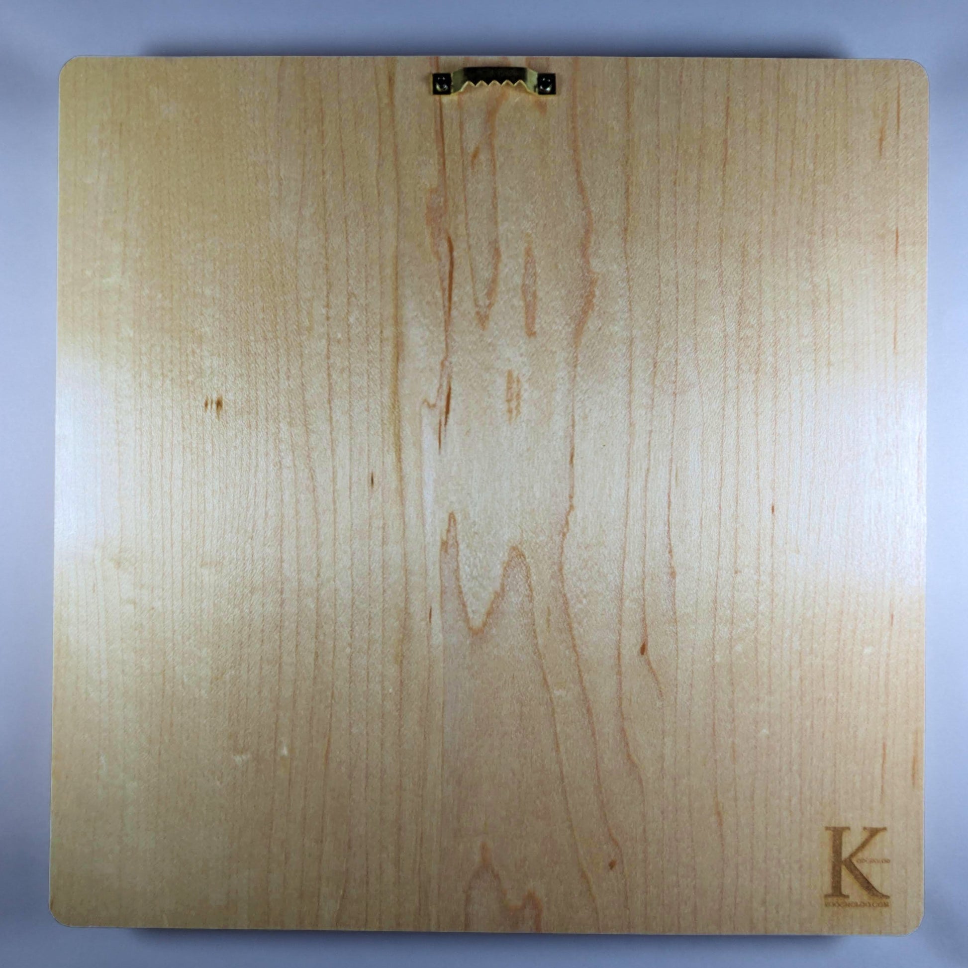Back of 11 inch hard maple wood wall plaque showing smooth natural grain, sawtooth hanger for easy wall mounting, and Koocholoo maker's mark, handcrafted Persian wood art ready to hang