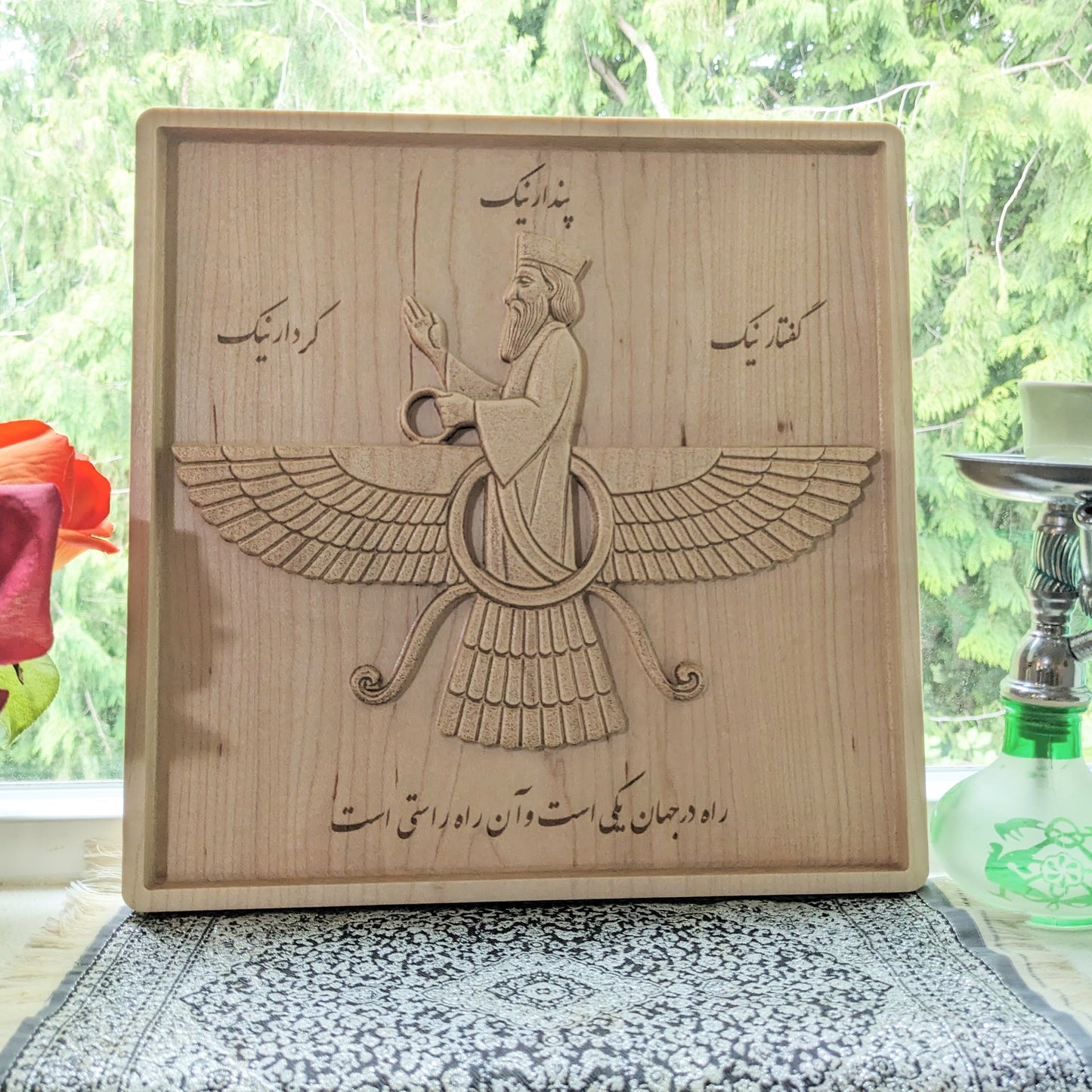 11 inch Faravahar wood relief displayed upright in a bright interior, showing its scale, Persian symbolism, and natural maple tone.