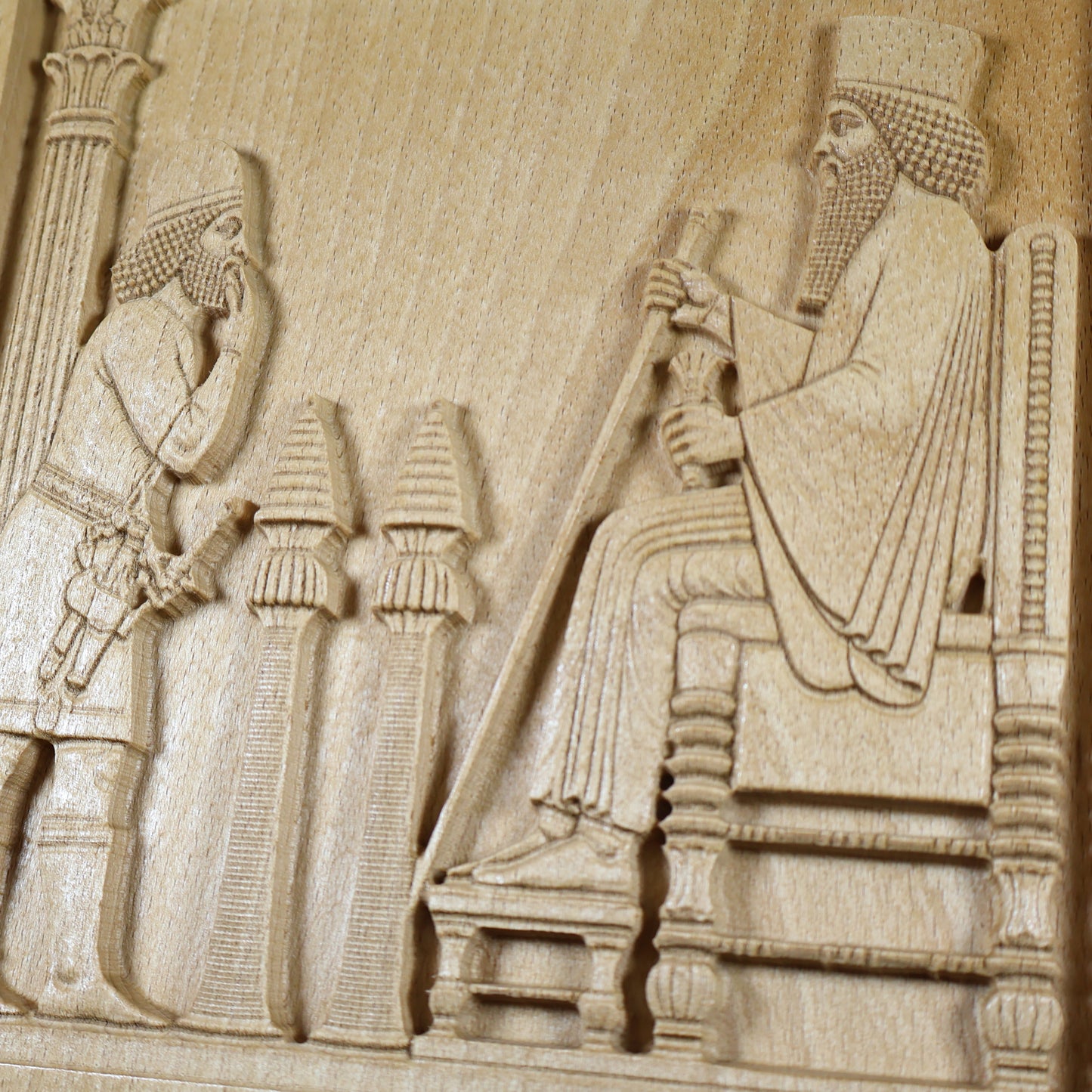Macro view of the Persepolis Royal Audience wood relief showing King Darius on the throne, an approaching attendant, ceremonial stands, carved robe details, and natural beech wood grain.