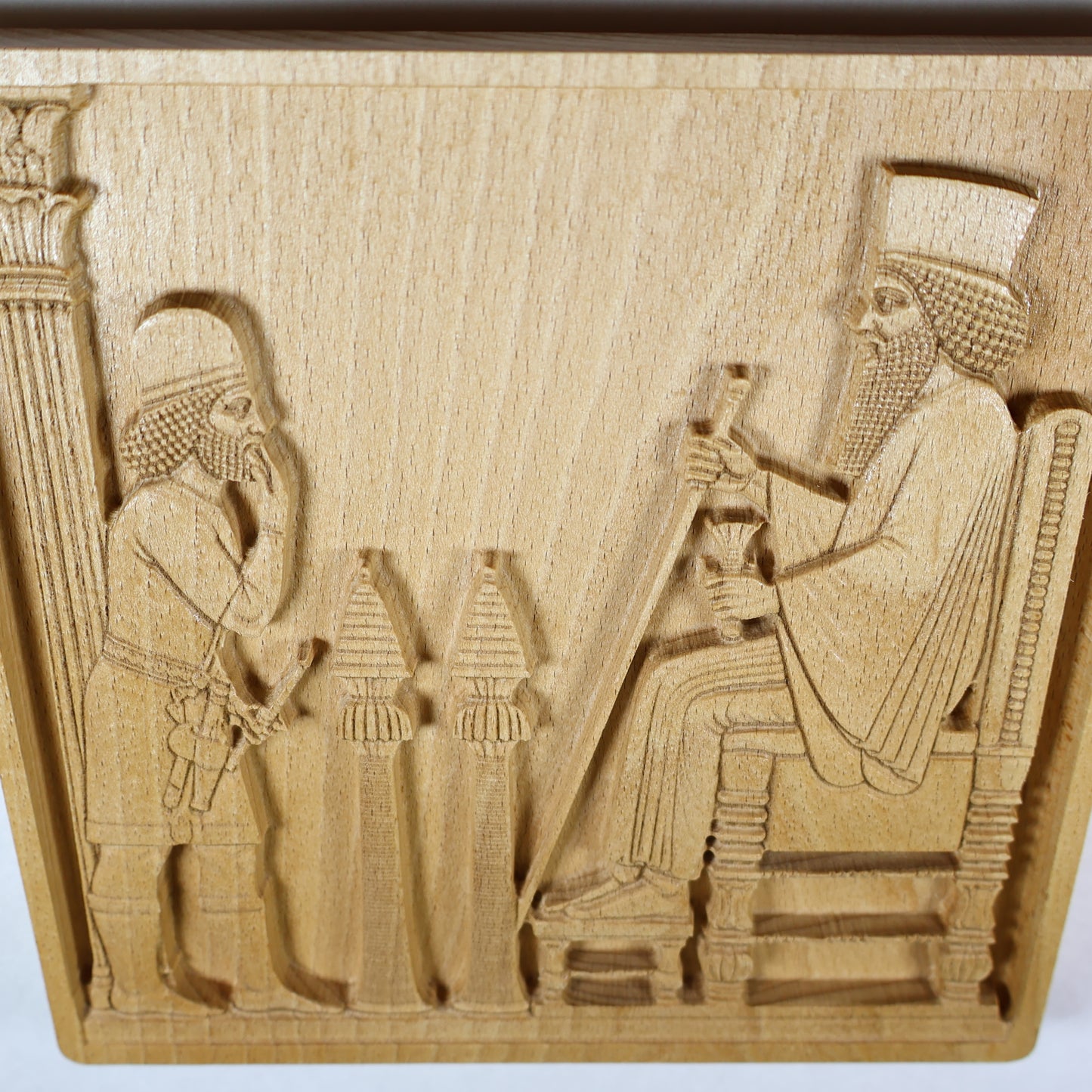 Overhead angled view of the Persepolis Royal Audience wood relief showing the seated king, approaching figure, ceremonial stands, throne, column edge, and natural beech wood finish.