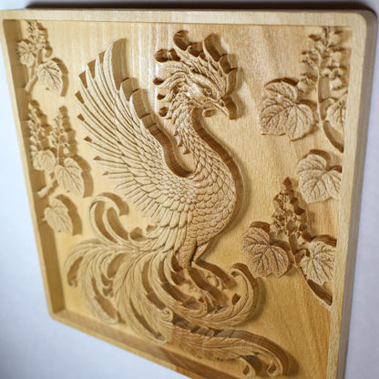 Angled display view of a Phoenix wood relief showing raised feather details, paulownia flowers, carved depth, and natural wood finish.
