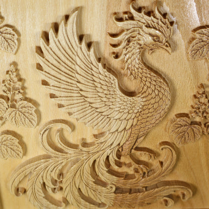 Close front view of a Japanese Phoenix wood relief showing the carved wing, curved neck, flowing tail, paulownia leaves, and wood grain.