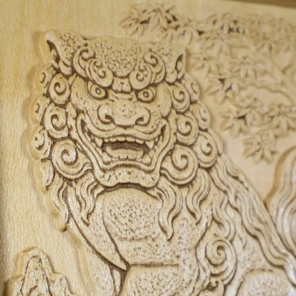 Close-up of a Japanese Komainu guardian lion dog wood relief showing the carved face, open mouth, curled mane, maple tree background, and natural wood finish.