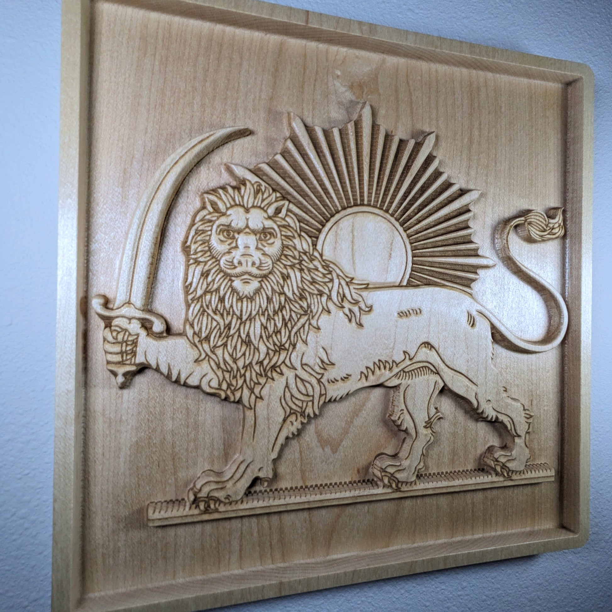 Wall-mounted Lion and Sun (Shir va Khorshid) hard maple wood relief shown from a low diagonal angle, highlighting carved 3D relief depth, raised lion, saber, sunburst, and framed border on wall