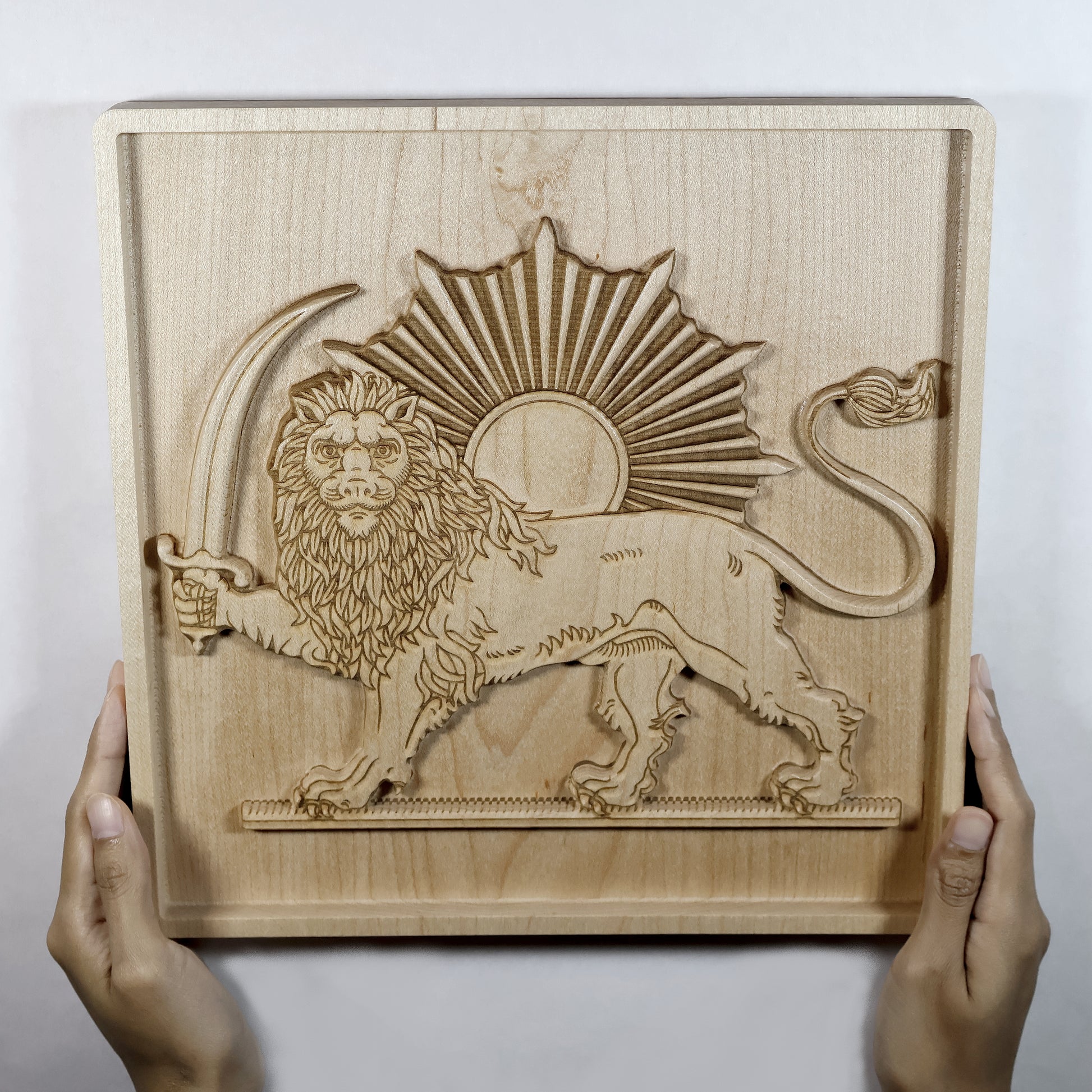 Person holding Lion and Sun (Shir va Khorshid) hard maple wood relief with both hands, showing full 11 inch carved panel size, raised lion figure, sunburst, and 3D relief depth, Persian wall art size reference