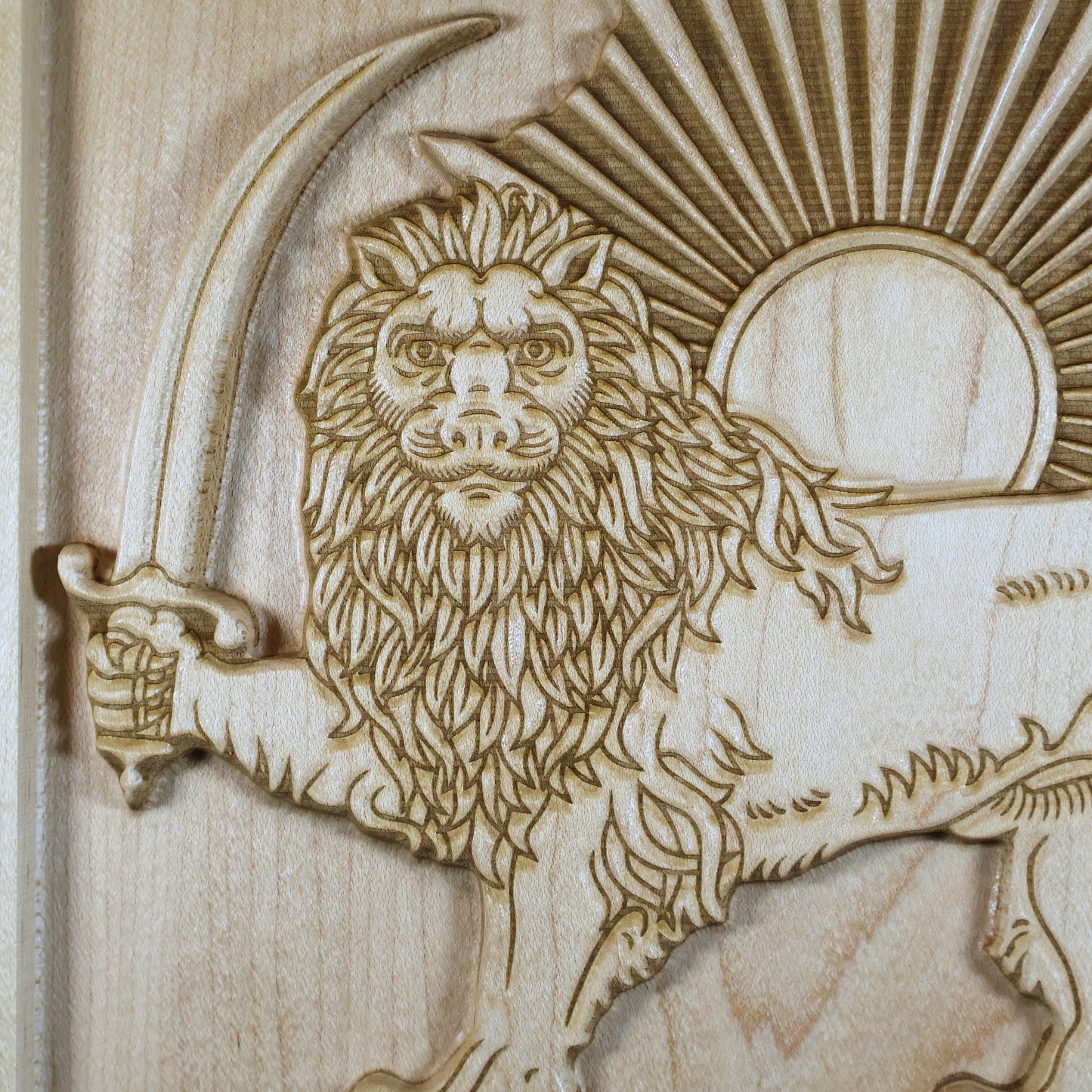 Macro detail of the Lion and Sun relief showing the lion face, crown, mane, sword, sun disk, and precision-carved rays.