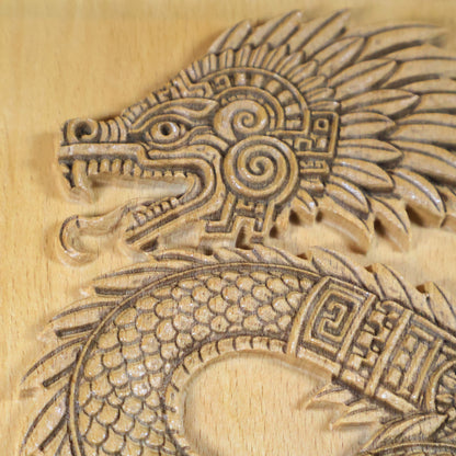 Extreme close-up of Quetzalcoatl serpent head carved in beech wood, revealing open fanged jaw, circular spiral cheek ornament, raised feather crest, geometric neck band, and fine CNC-engraved texture