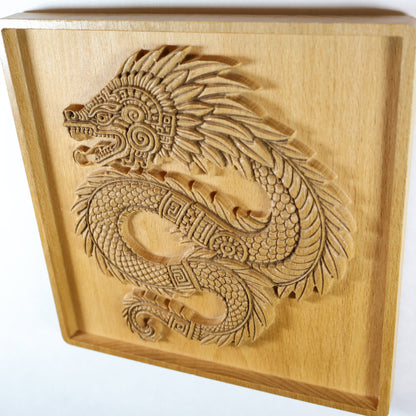 Corner angle view of Quetzalcoatl beech wood relief showing plaque thickness, recessed border frame, coiled feathered serpent carving, and smooth sanded edges, handcrafted Aztec wood wall art ready to hang