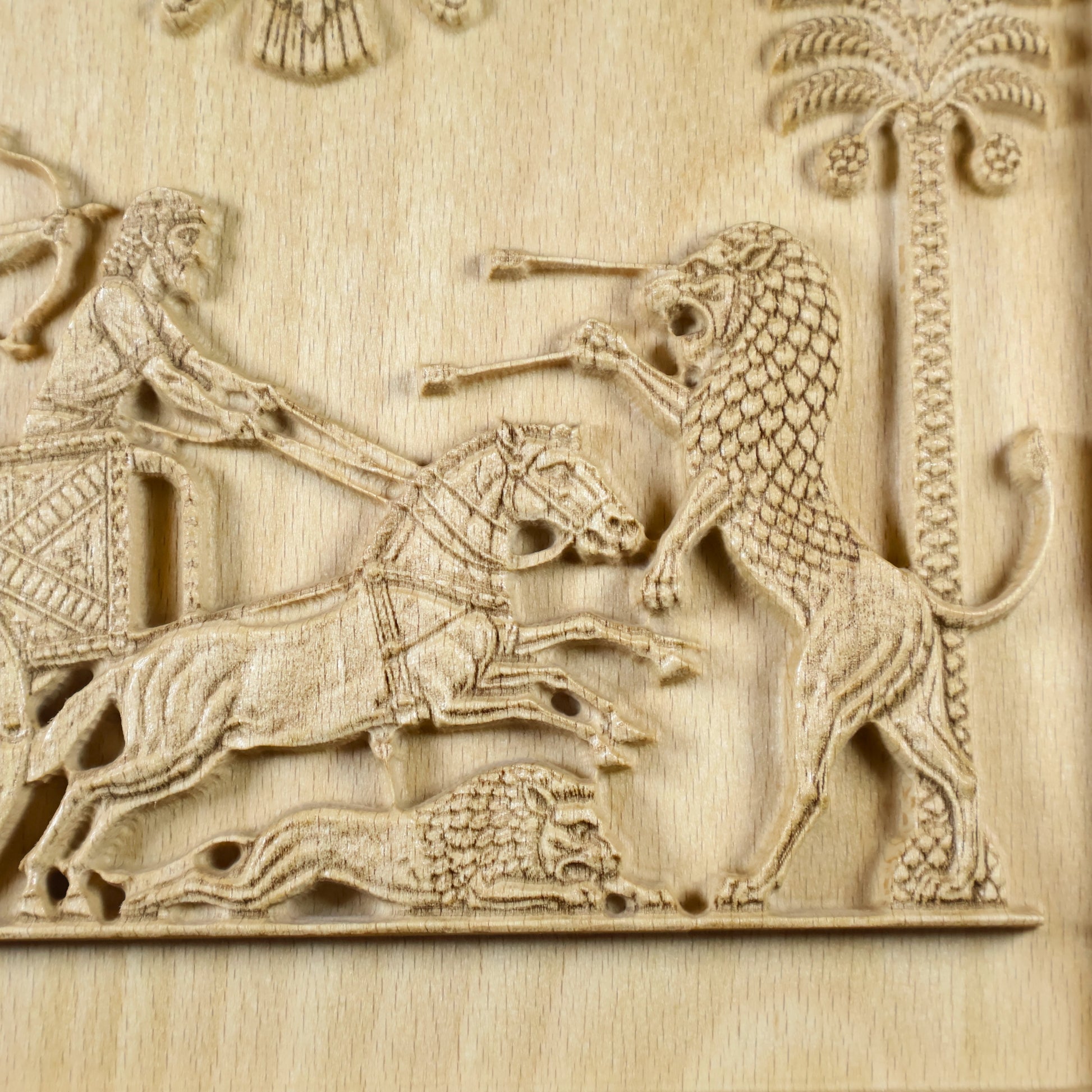 Macro detail of the Darius relief showing the lion’s mane, galloping horses, fallen lion, reins, and raised wood-carving texture.