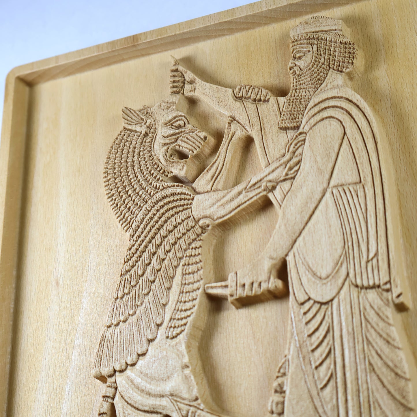 Close side detail of Shahriar and the Lion wood relief showing the Persian figure’s beard, robe, dagger, and the lion’s carved face, mane, and raised relief depth.