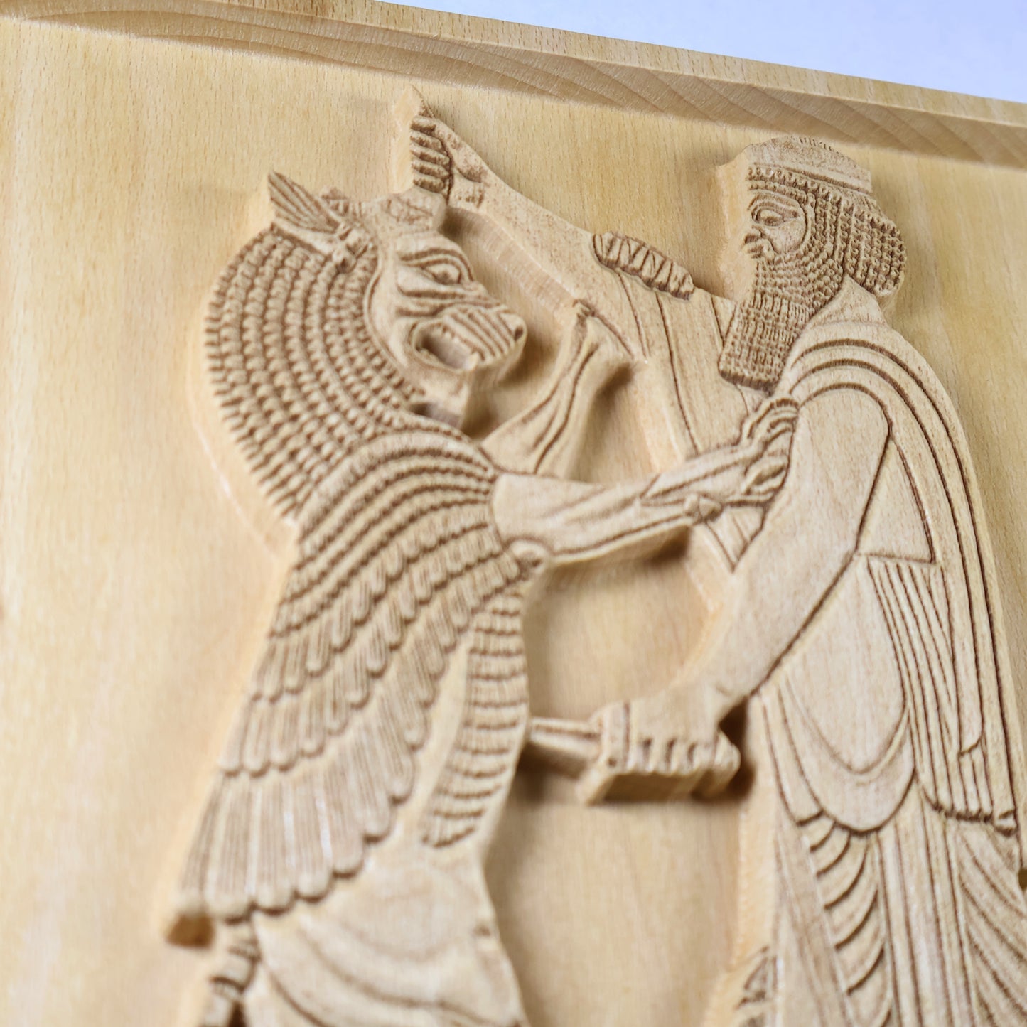 Macro side view of Shahriar and the Lion wood relief showing the carved lion, Persian figure, dagger, beard detail, robe lines, and raised natural wood relief.