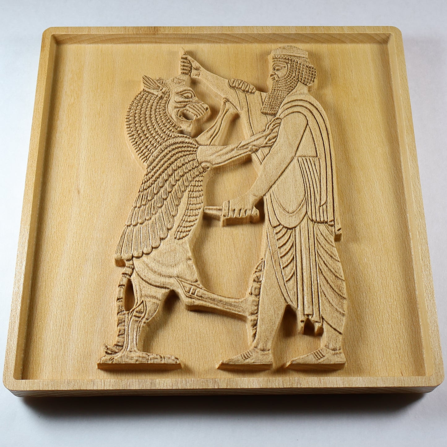 Angled view of Shahriar and the Lion wood relief showing a Persian figure facing a raised lion, with carved clothing, weapon details, relief depth, and natural wood finish.