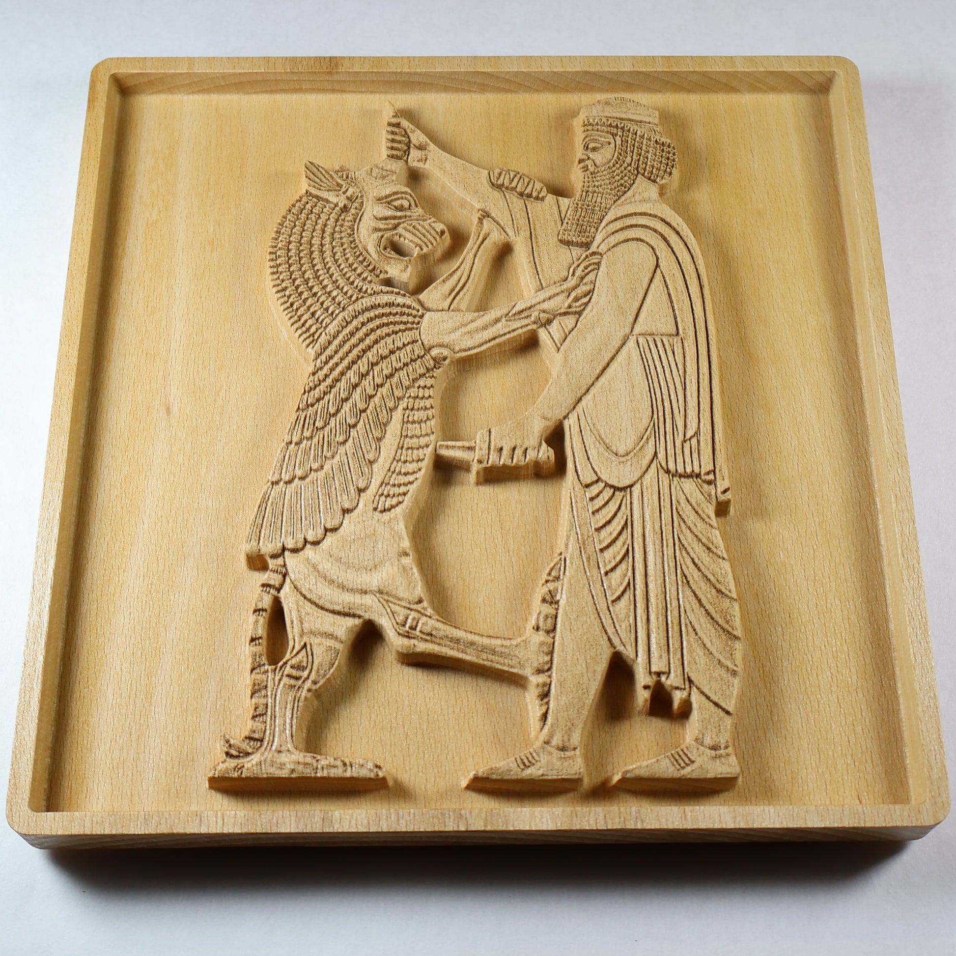 Angled view of Shahriar and the Lion wood relief showing a Persian figure facing a raised lion, with carved clothing, weapon details, relief depth, and natural wood finish.