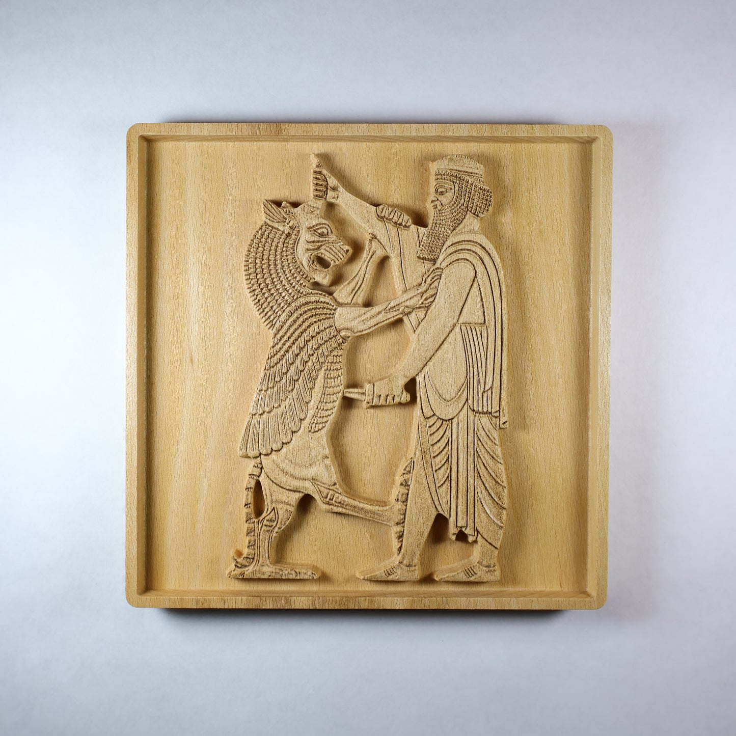 Front view of Shahriar and the Lion wood relief showing a carved Persian figure facing a lion, with detailed clothing, raised relief depth, square frame, and natural wood finish.