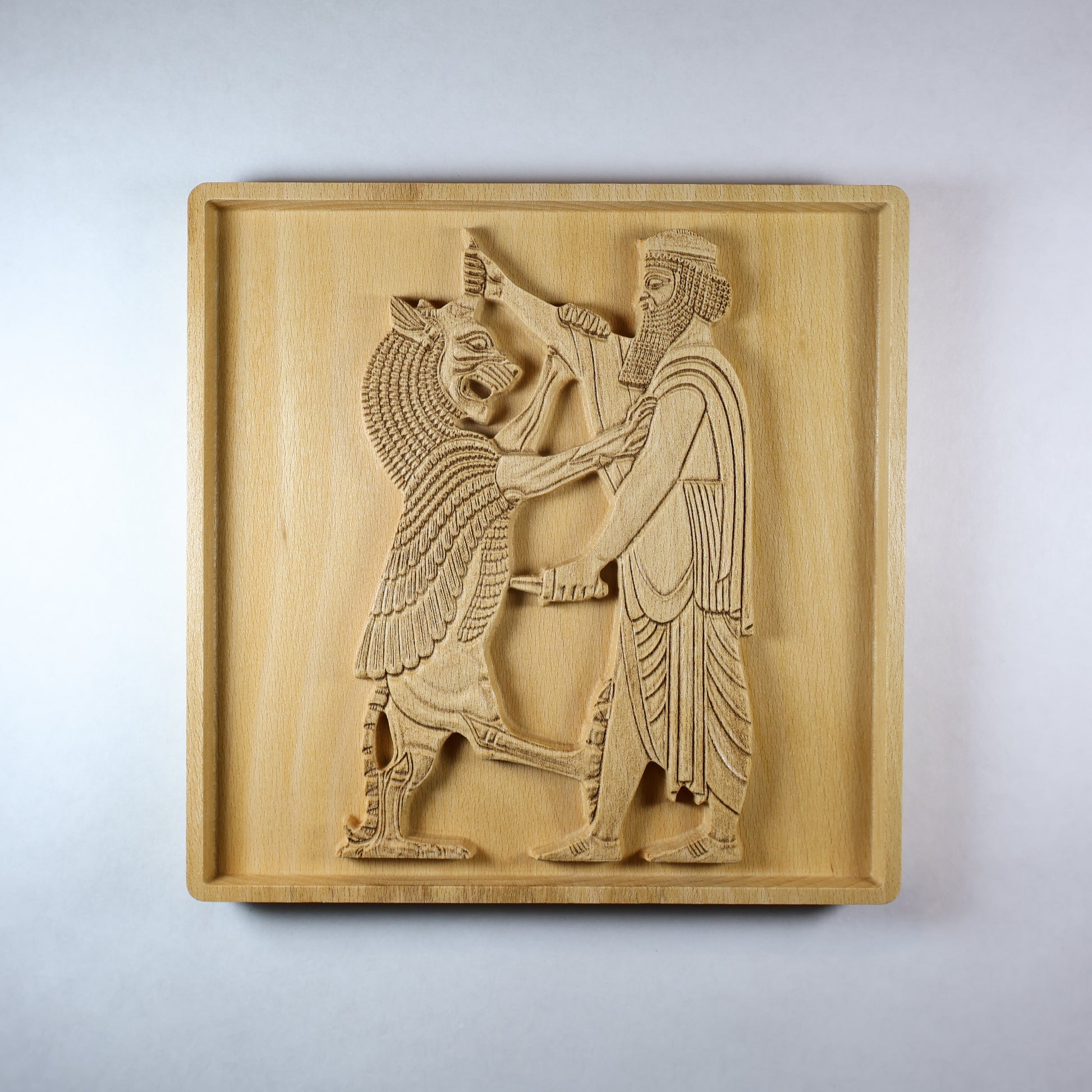 Front view of Shahriar and the Lion wood relief showing a carved Persian figure facing a lion, with detailed clothing, raised relief depth, square frame, and natural wood finish.