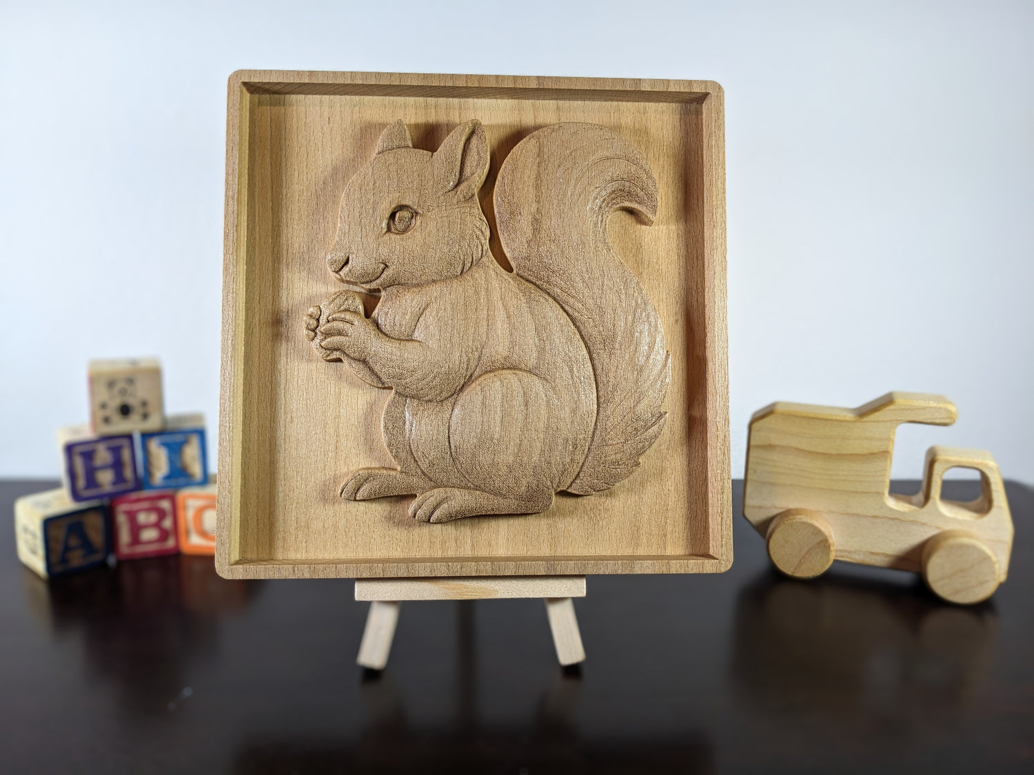 Wooden squirrel art in the foreground with blocks and wooden toy car in the background