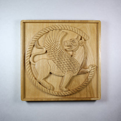 Front view of an Achaemenid Winged Lion Roundel wood relief with a carved Persian griffin, circular border, feathered wings, and natural wood finish.