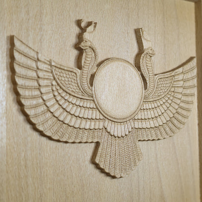 Close-up of an Egyptian Winged Sun Disk wood relief showing the carved sun circle, twin cobras, feather details, raised edges, and natural beech wood grain.
