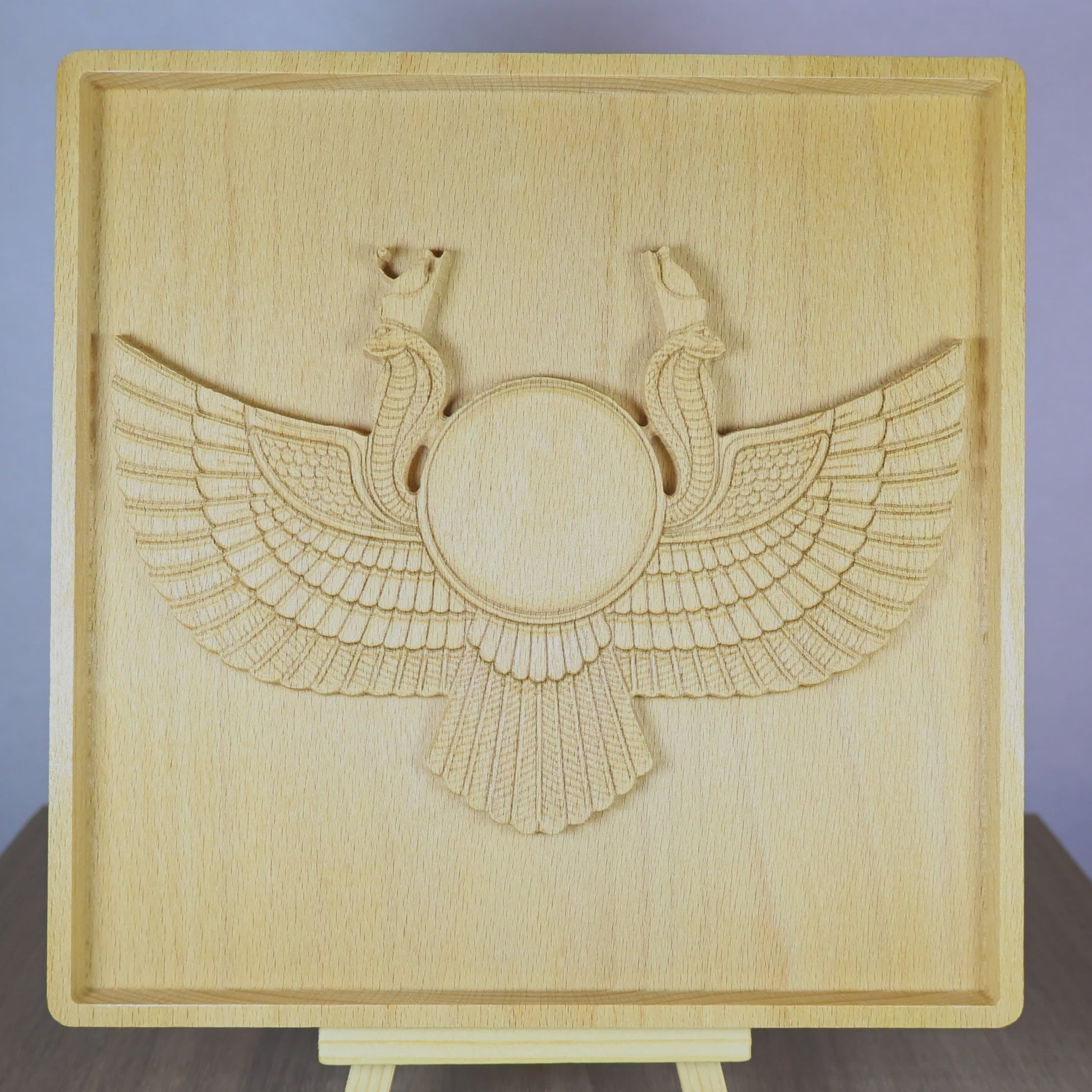 Rotating tabletop video of an Egyptian Winged Sun Disk wood relief, showing the front and angled side views of the carved Ra-Horus sun symbol, wide feathered wings, twin uraeus cobras, raised bas relief depth, and natural beech wood finish.