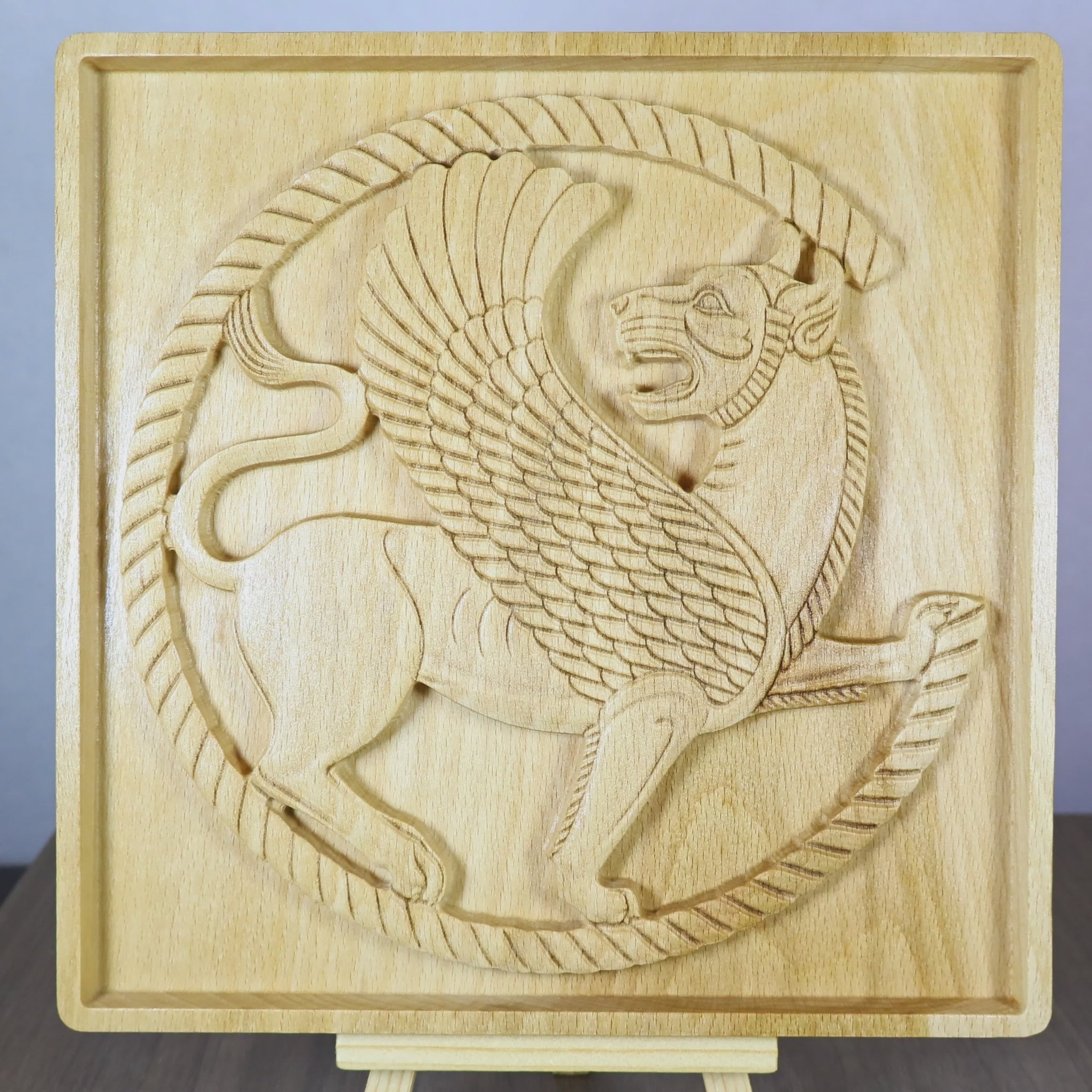 Rotating tabletop video of an Achaemenid Winged Lion Roundel wood relief, showing the front and angled side views of the Persian winged lion, carved roundel border, raised griffin details, and natural beech wood finish.