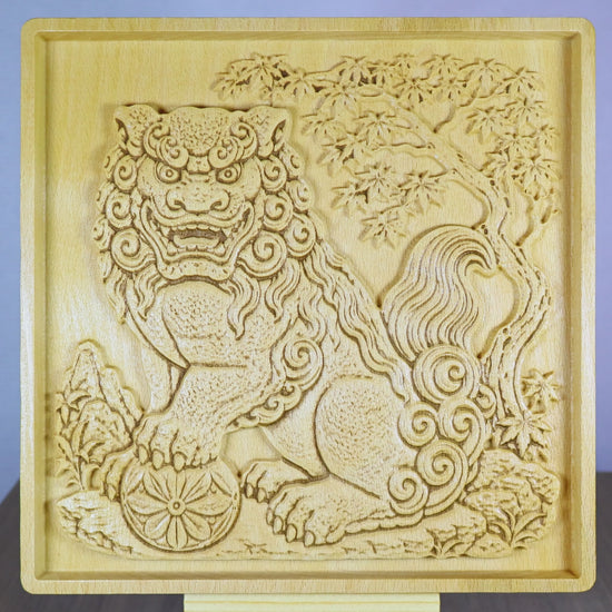 Rotating tabletop video of a Japanese Komainu guardian lion dog wood relief, showing the front view and angled side views with carved temple guardian details, paw on floral ball, curled mane, tree background, raised bas relief depth, and natural wood finish.